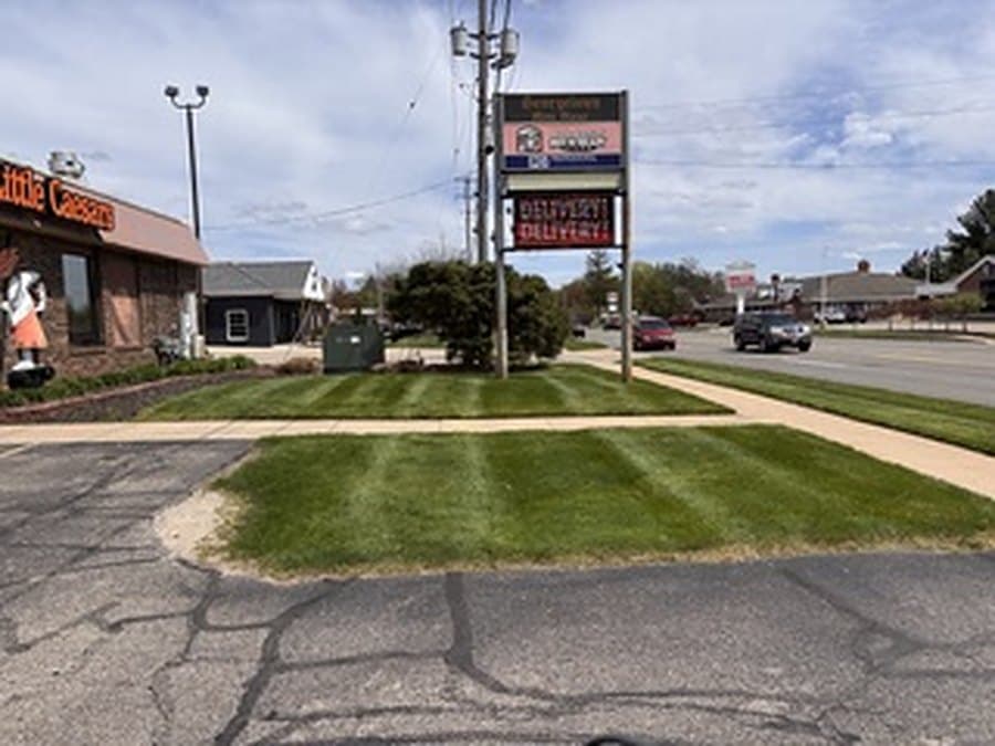 Freshly mowed and edged lawn along a commercial storefront and sidewalk