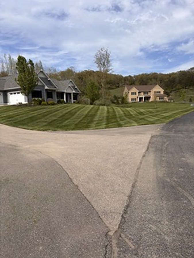 Sweeping striped lawn wrapping around a large home and drive