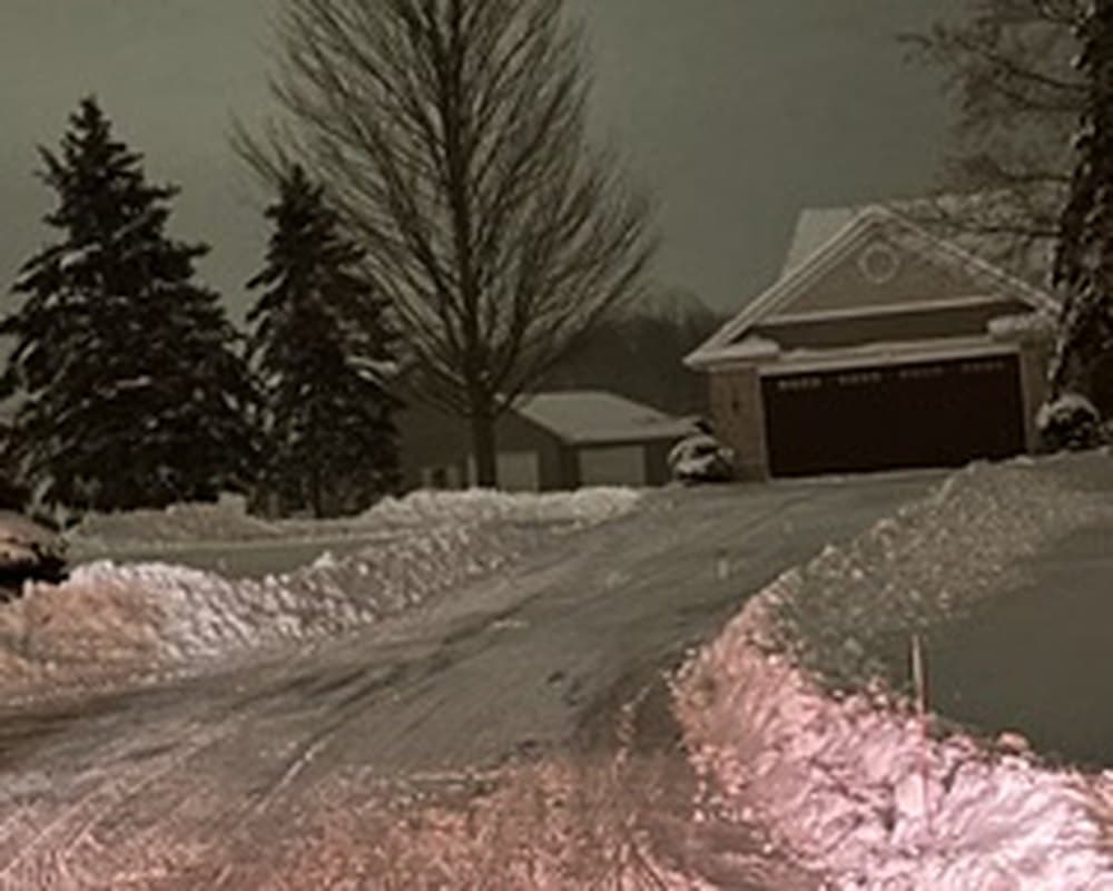 Residential driveway plowed clean at night with snow banked on both sides